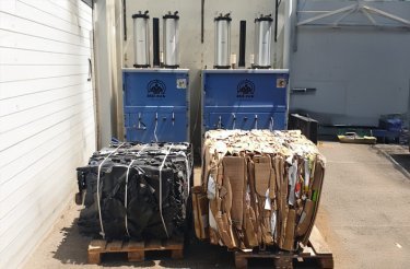 Two cardboard bales in front of blue balers